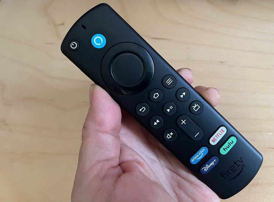 يد تمسك جهاز التحكم عن بعد صوت تلفزيون النار